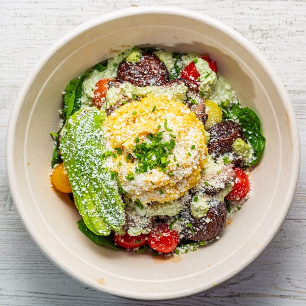 EGGDOSE breakfast bowl with scrambled eggs, avocado, meatballs, tomatoes, and green sauce.